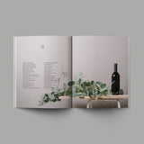 The Book of Proverbs Soft Cover 9: Wooden table with green foliage and bottle